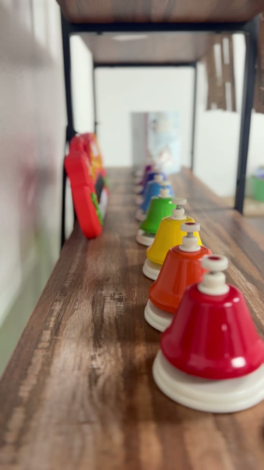 Una fila de campanas de colores en un estante de madera