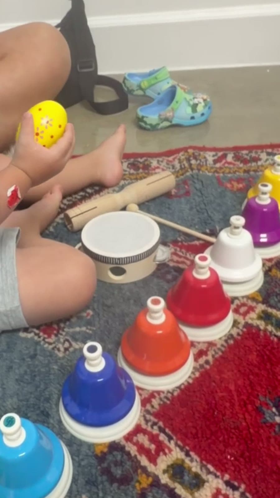 Campanas de colores, una pandereta y un piecito sobre una alfombra