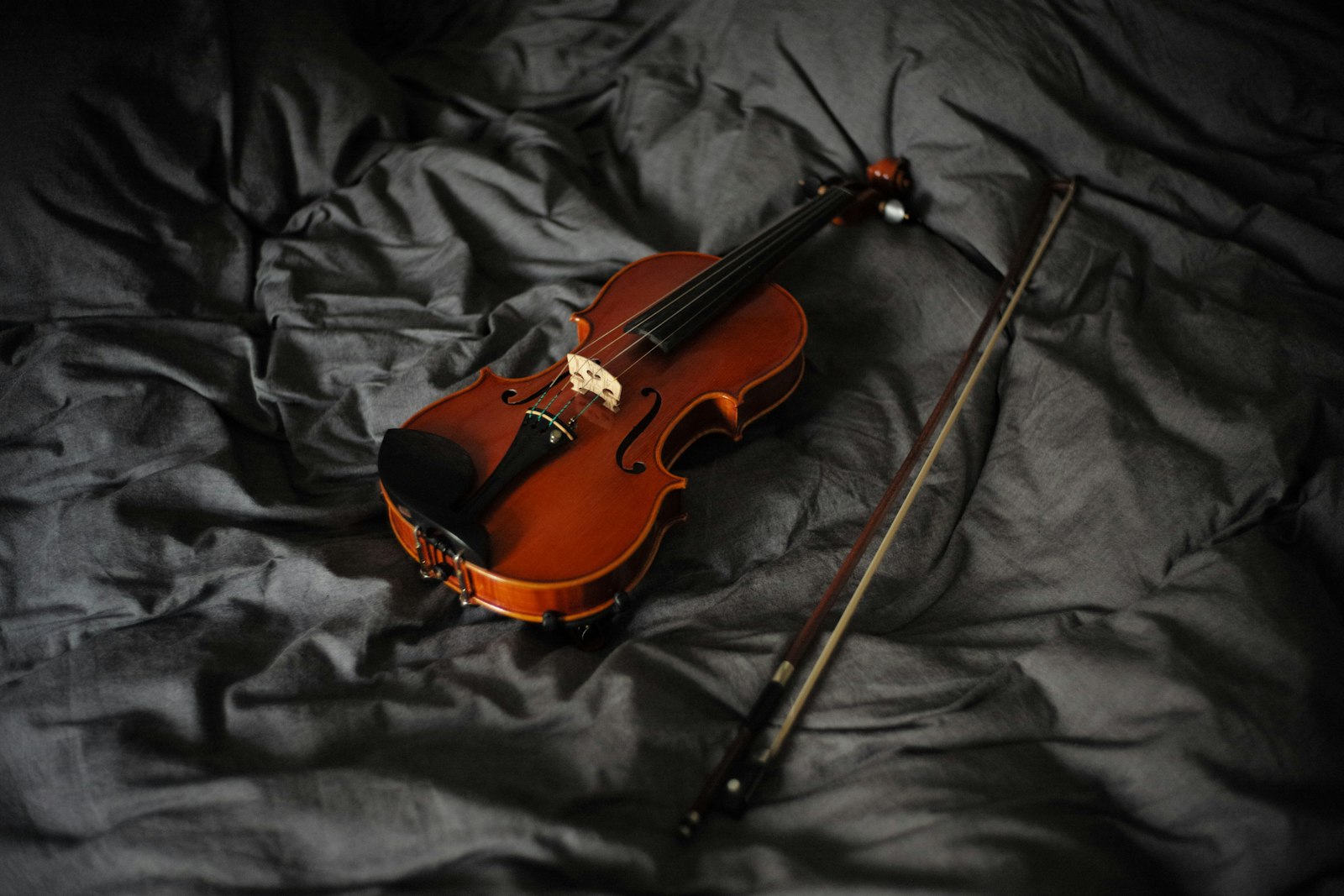 Un violín y su arco sobre una tela oscura